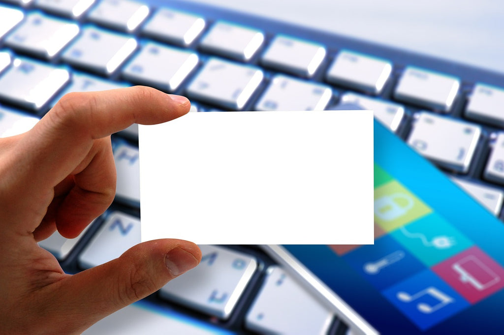 Person holding business card in front of keyboard