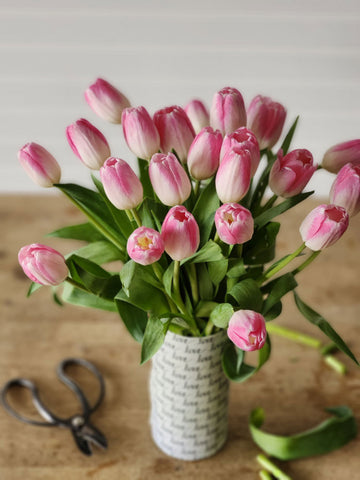 a bouquet of pink tulips in a cylinder vase