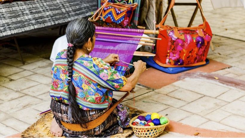 Maya woman weaving while wearing a huipil blouse