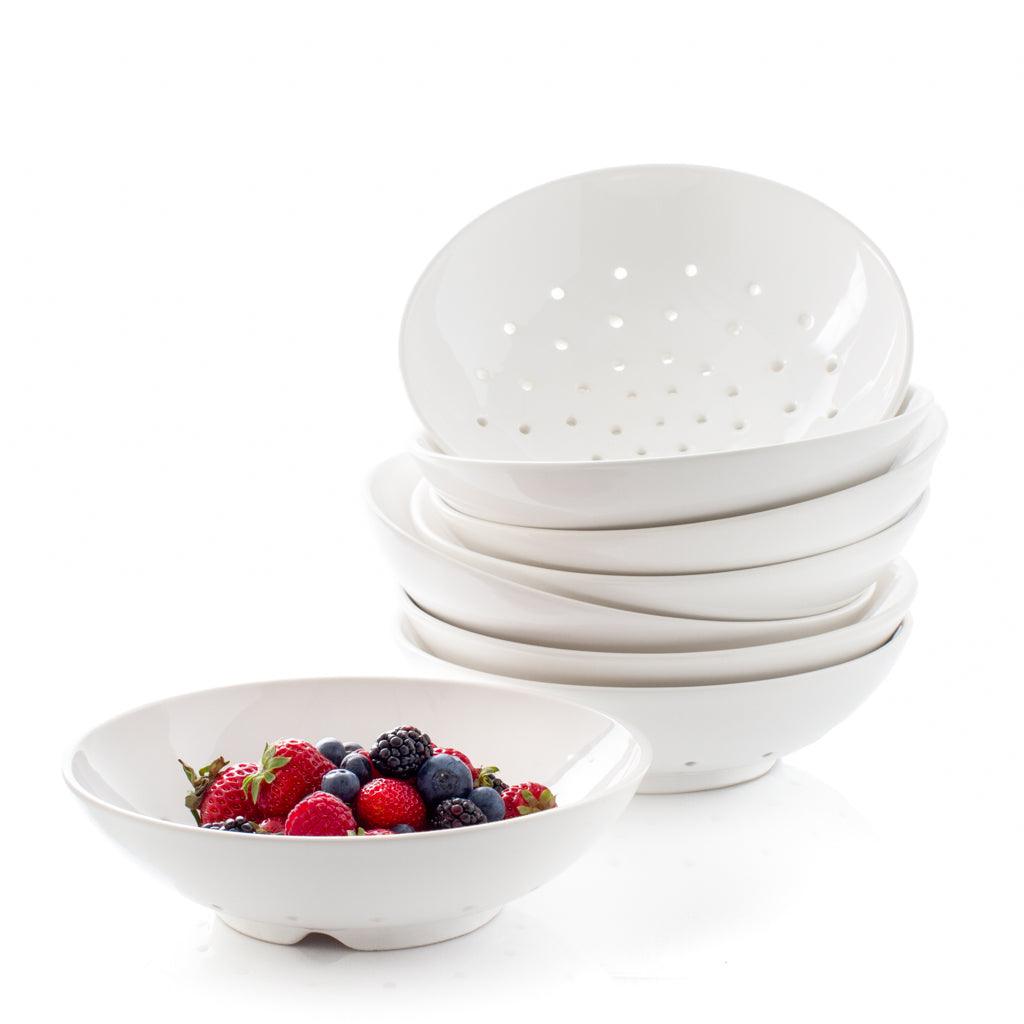 Stack of berry bowls with drainage holes and a berry bowl holding mixed berries.