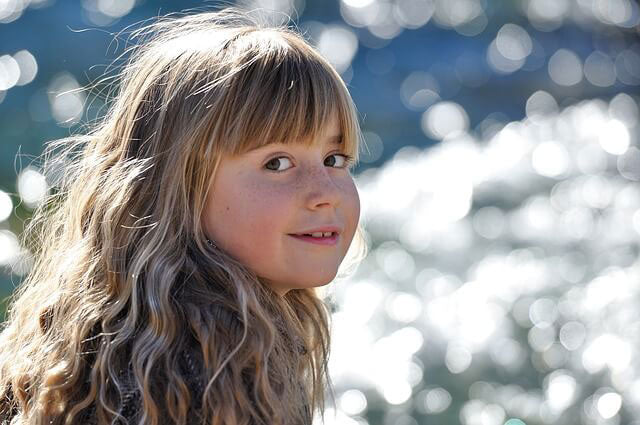 child sitting by the river during the day