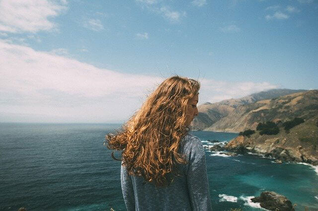 woman on top of a cliff facing the beach