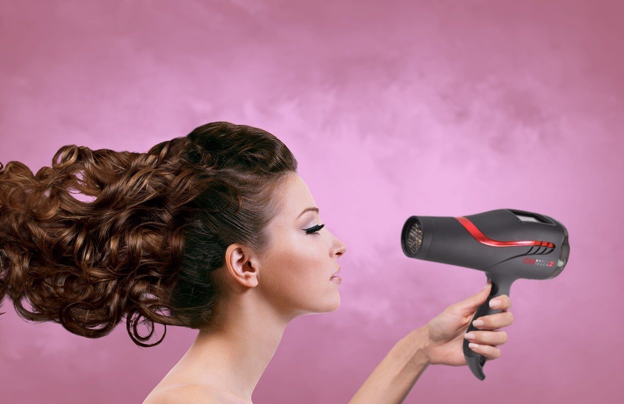 woman drying her long hair with a blower
