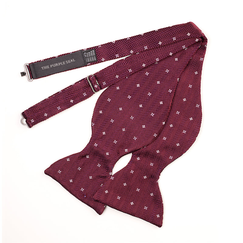 Large bow tie in bordeaux and purple herringbone jacquard silk with flower/cross detail, self-tie, by The Purple Seal. Handmade in Como, Italy