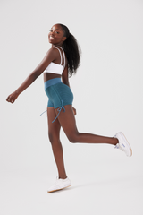 girl posing wearing luna scrunch bum shorts in blue and classic crop top in white