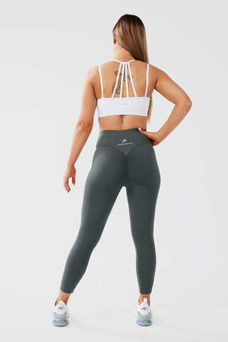 Girl posing hand on hip from behind, wearing Luna X Seamless Scrunch Bum leggings in khaki and white classic crop top