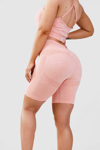 Girl posing hand on hip wearing calypso seamless shorts and sports bra in pink marl, back