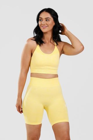 Girl wearing yellow calypso seamless shorts and sports bra front