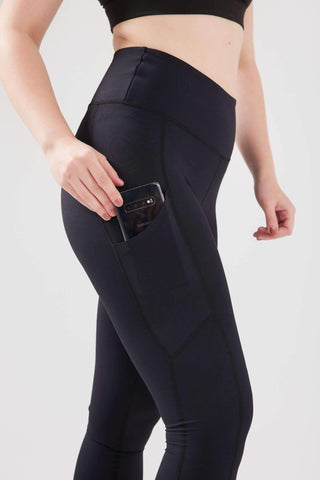 Close up girl holding phone in pocket of black Luxe Pocket Leggings