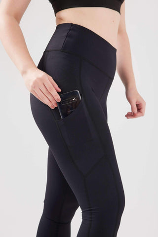 girl pulling phone from pocket of black luxe pocket leggings