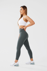 Girl looking to the side posing hand on hip, wearing Luna X Seamless Scrunch bum leggings in khaki and white classic crop top