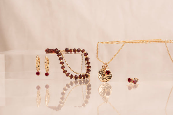 Garnet gold jewellery hanging with a cream background