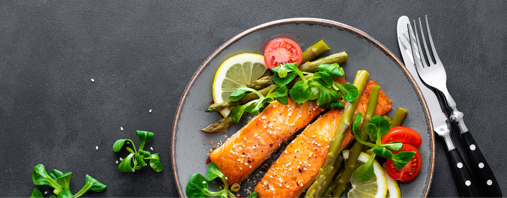 Lachs mit grünem Spargel auf einem grauen Teller serviert.