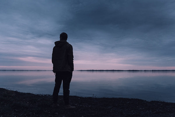 man staring on the beach at night time staring off into the ocean