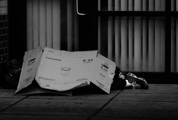 homeless man sleeping under a cardboard box blanket