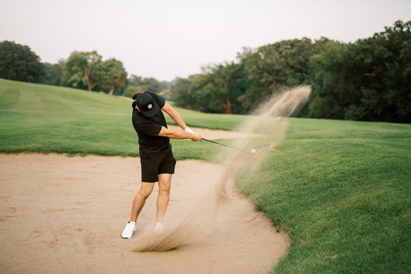 golfer hitting high shot out of bunker