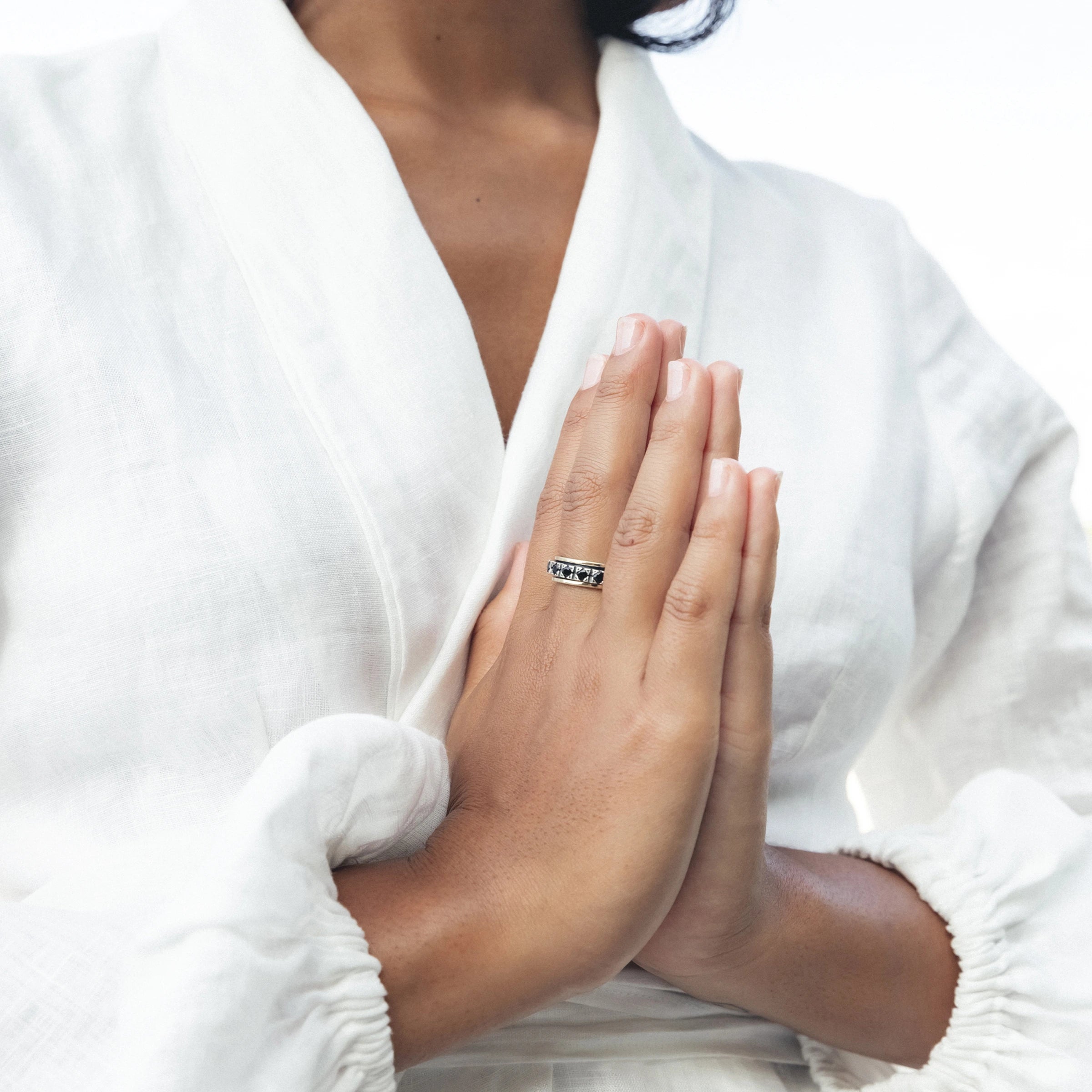 Close-up of hands in a prayer position wearing a silver meditation ring, symbolizing mindfulness and grounding during yoga practice for anxiety relief.
