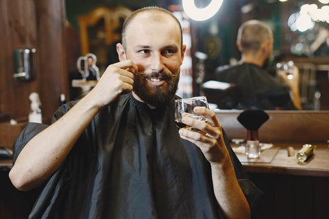 homem de bigode sentado na barbearia