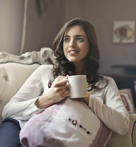woman sitting on couch with coffee cup relax after organize her living space
