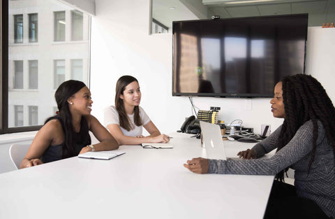 three women in meeting room having interview discussing work terms