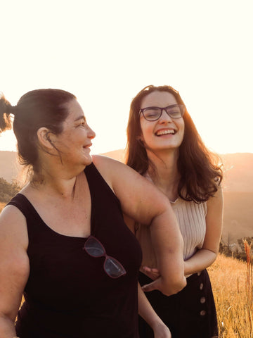 mother and daughter laughing while walking outside during sunset