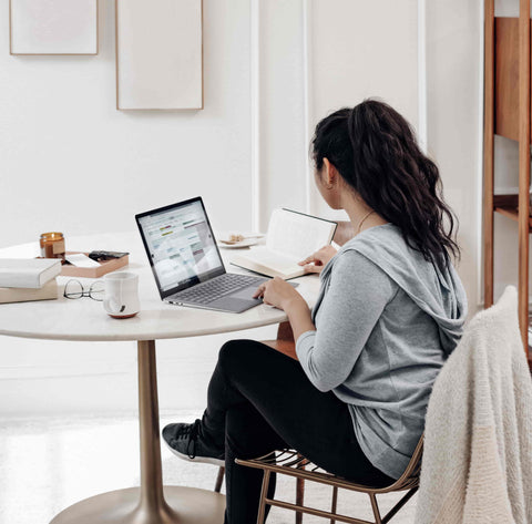 woman working from home at small table with laptop