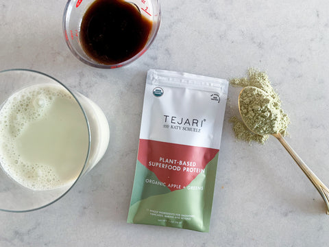 measuring cup with coffee, Tejaru Organic Apples + Greens Blend pouch, milk, and date syrup