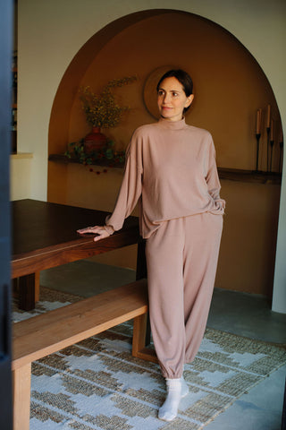 Rachel Pally standing leaning on a table with her hand wearing fashionable loungewear