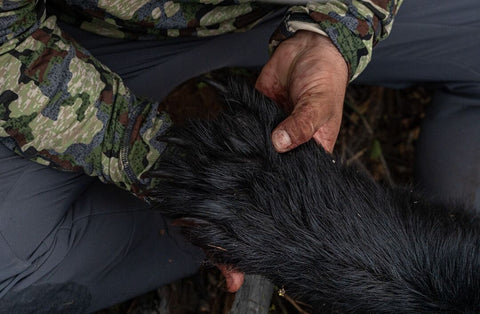 Hunter holding the paw of a black bear