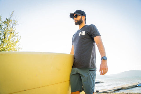 man wearing upf board shorts holding paddleboard