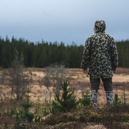 allclima-boot baiters in exposed camo-on a man-in a field-wearing a camo jacket