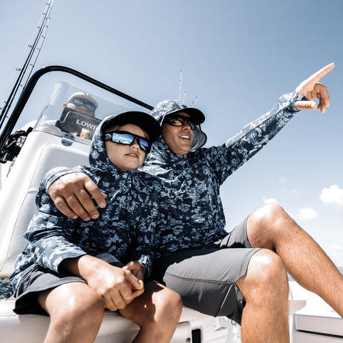 father and son wearing sun shirts on a fishing boat