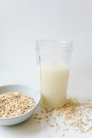 Oats beside jar of homemade oat milk