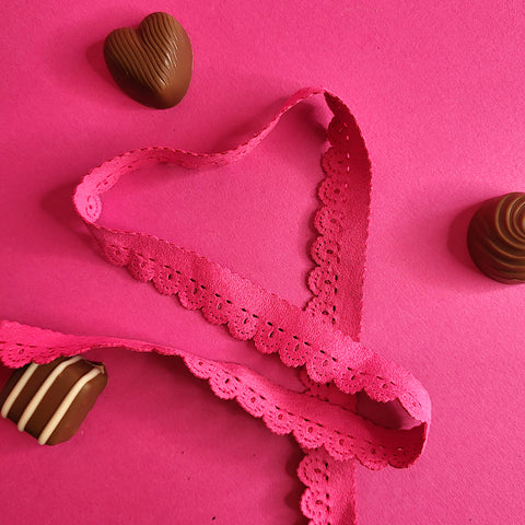 8139 07 Pink Suedette Trim sits on a pink background in a heart shape surrounded by Milk Tray chocolates