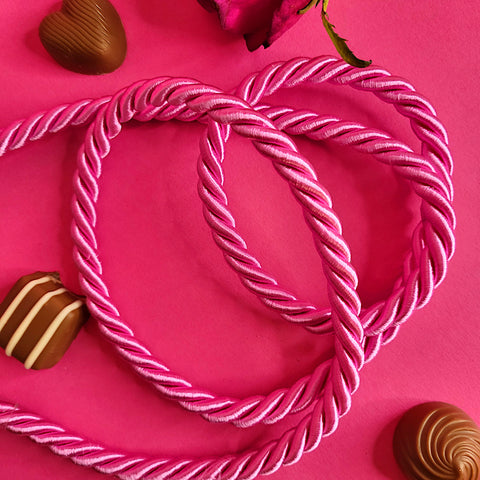 9995 9mm 169 Millennial Pink Twisted Cord is laid freely on a pink background surrounded by Milk Tray Chocolates