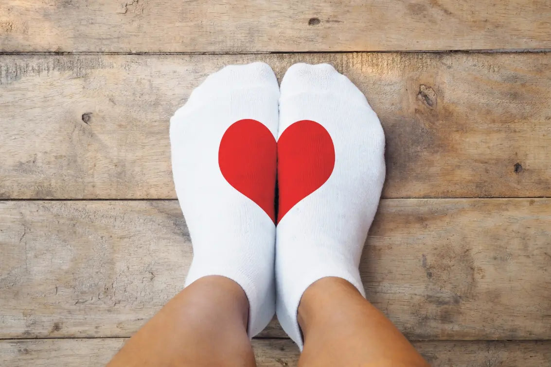 Two feet in white socks with red hearts on them.
