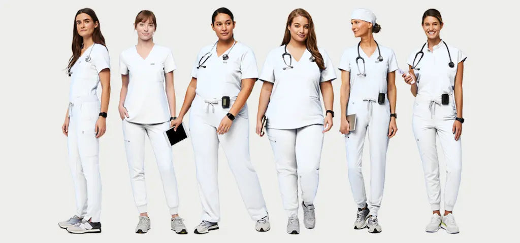 A group of female lab scientists wearing white scrub uniforms on a light grey background.