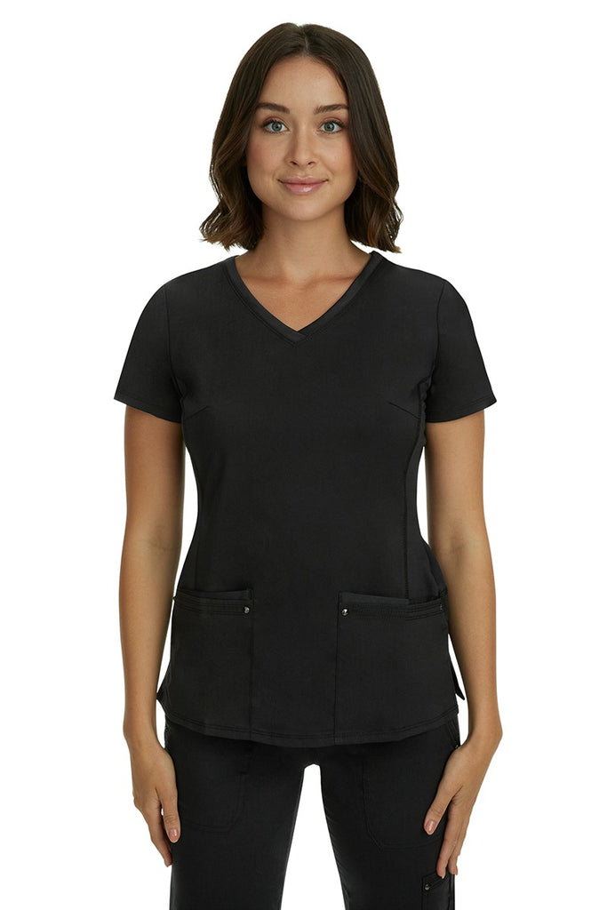 A young LPN wearing a Purple Label Women's Juliet Yoga Scrub Top in Black featuring 2 front patch pockets.