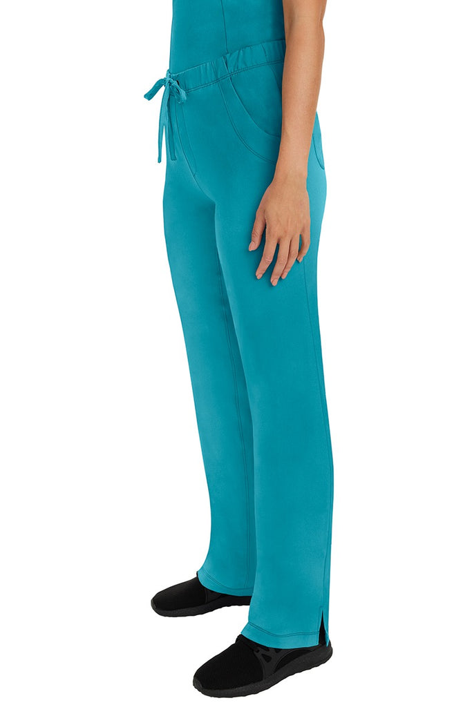 A woman Home Care Registered Nurse wearing a pair of HH-Works Women's Rebecca Multi-Pocket Drawstring Pants in Teal featuring side slits for additional range of motion.