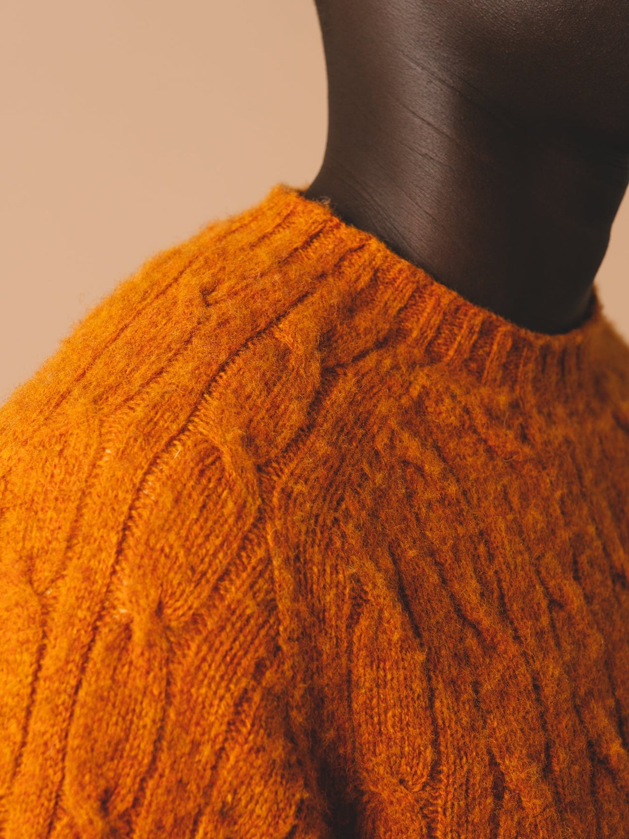 A man wearing a Scottish cable knit sweater in orange.