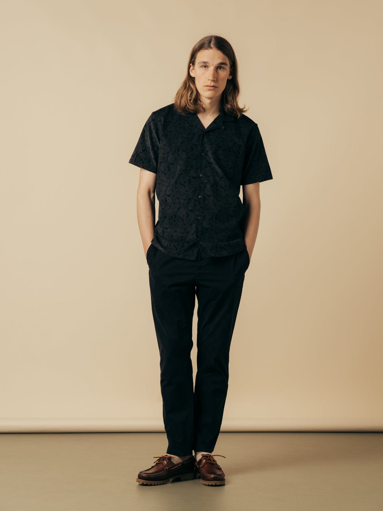 A model wearing a pair of black slim tapered trousers.