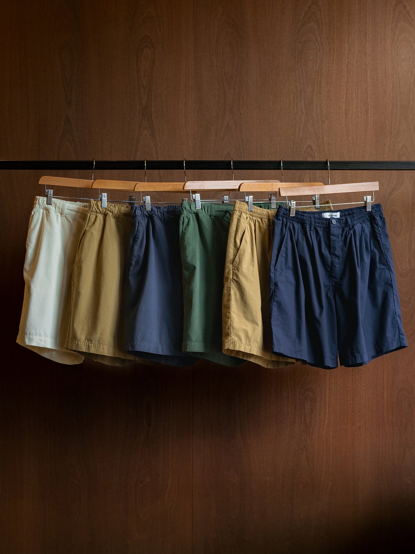 Six pairs of shorts hanging up from the KESTIN SS24 Collection.