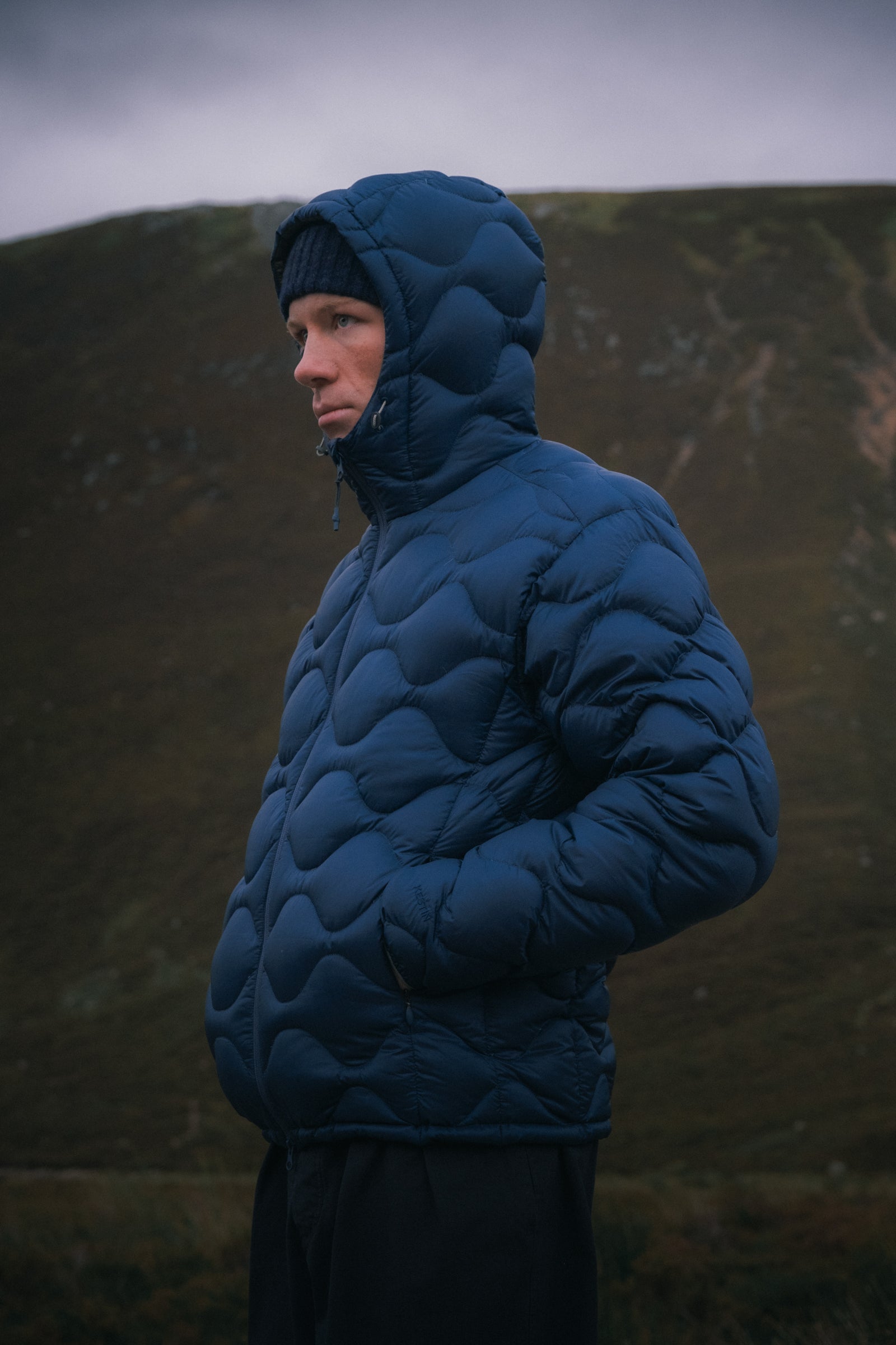 A man wearing a technical performance down jacket in the Scottish mountains.