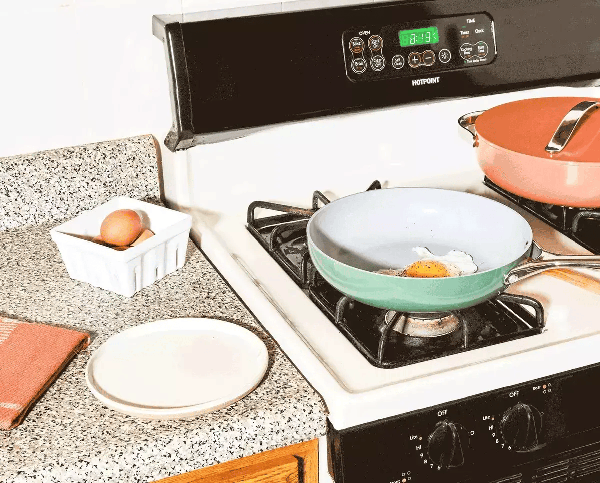 Fried egg on a pan, with two eggs in a basket and kitchen background.