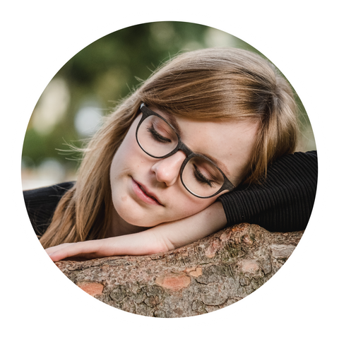 Woman with glasses laying on a tree bark