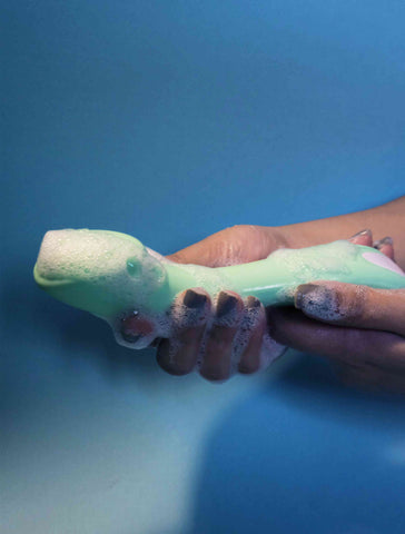 mint green spot vibrator for women being hand washed with soap bubbles and water