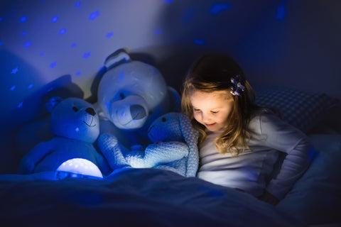 child reading in bed with night light