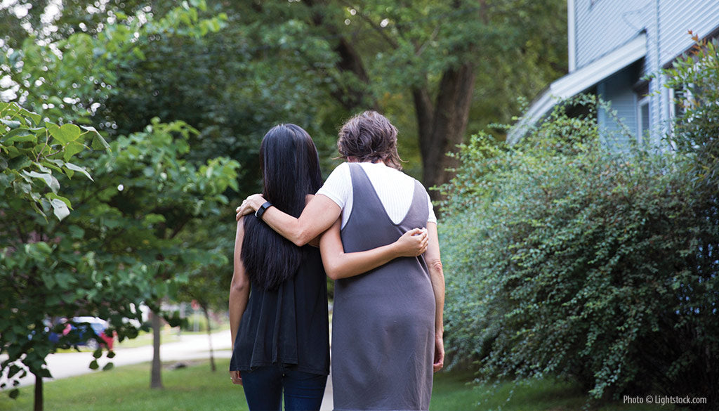 Two people with their backs to the camera and their arms around each other.