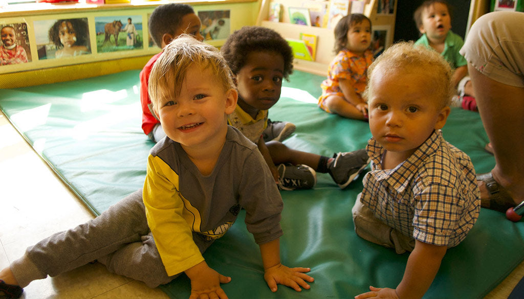 Children playing on a green floor mat.