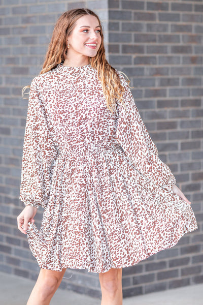 Model Wearing a White Printed Dress Against a Grey Brick Background